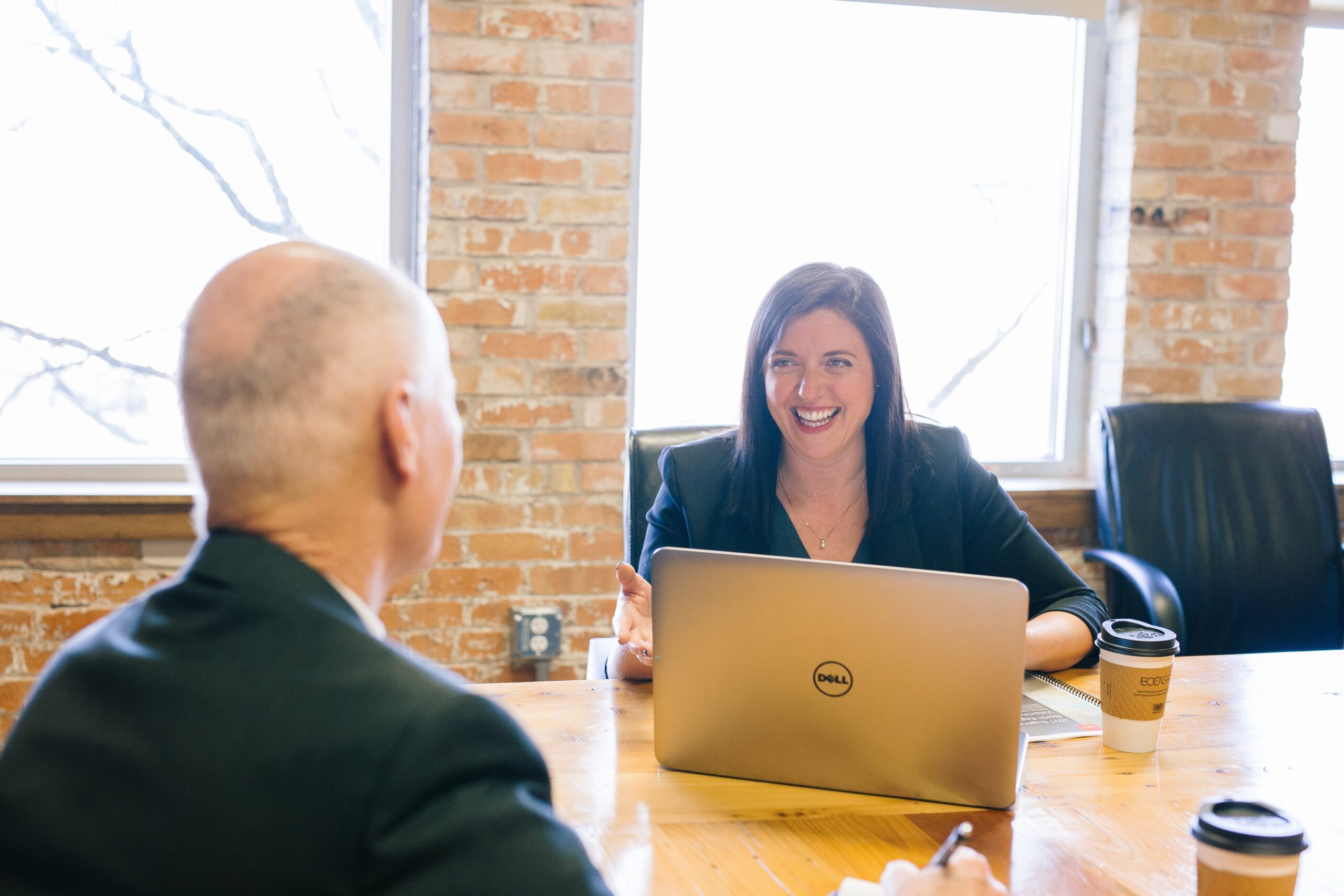 Man and smiling woman at a table with laptop and coffee