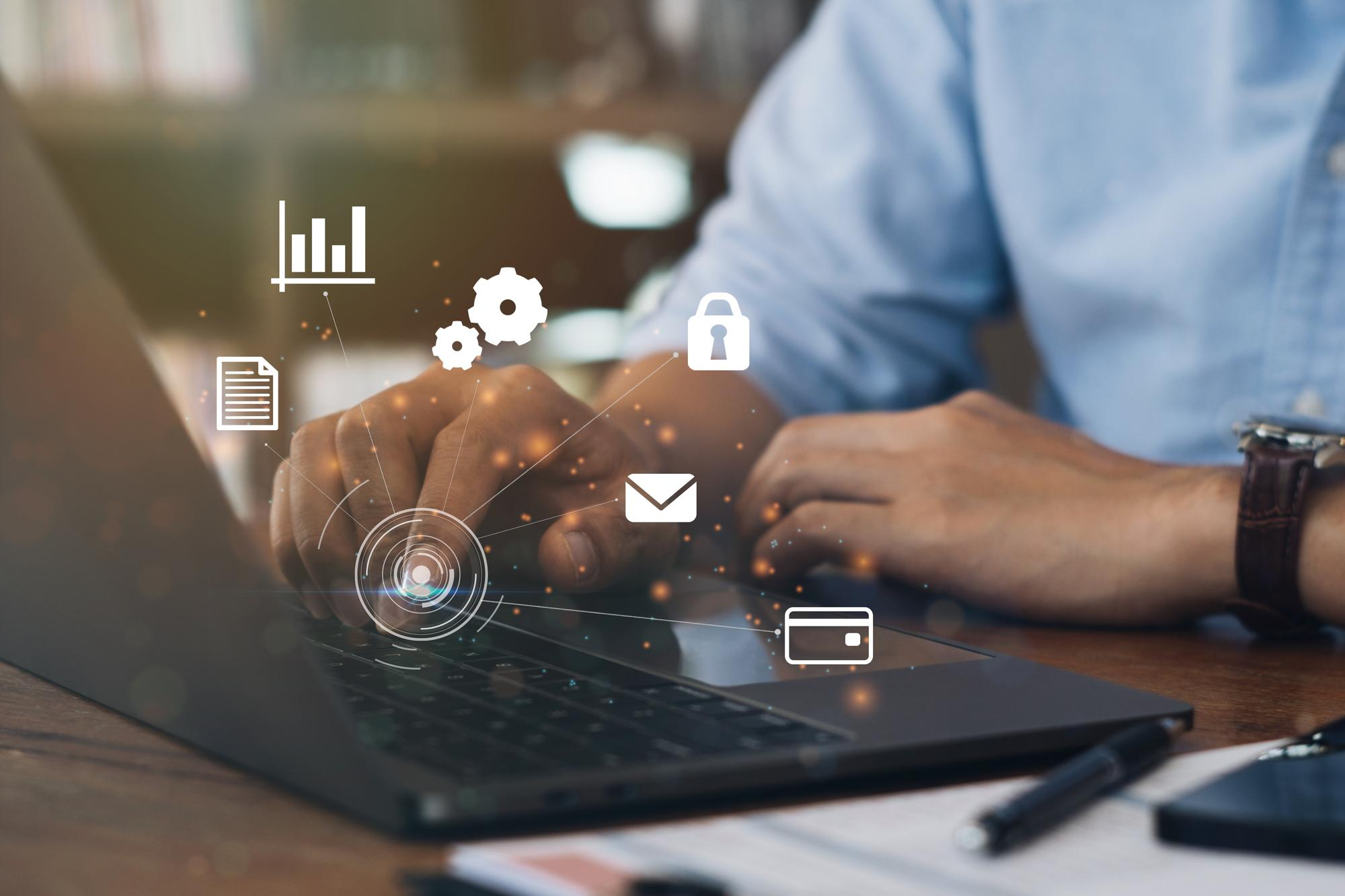 Digital icons representing different systems overlaid on an image of a person clicking on a laptop
