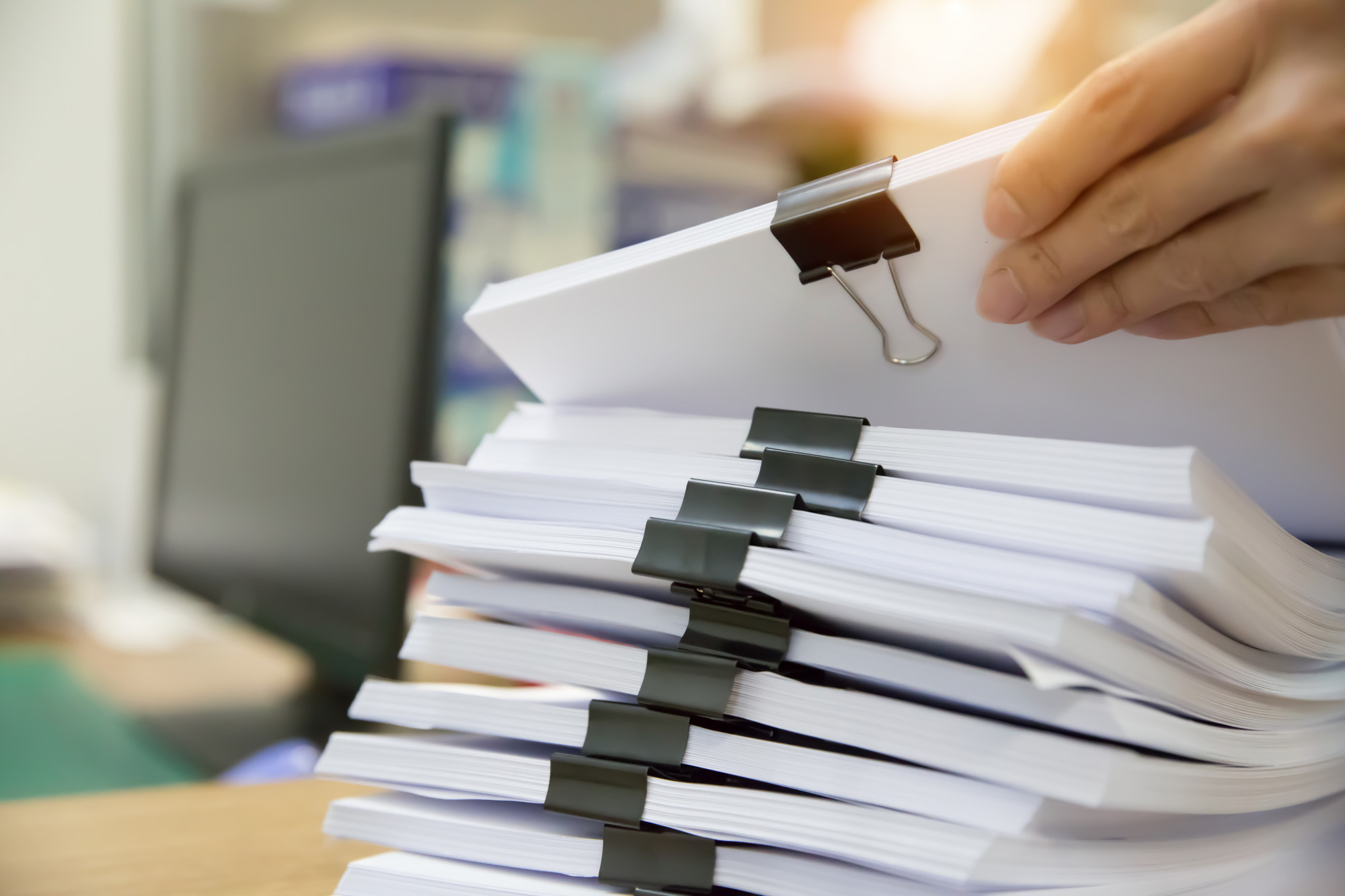 Stacks of project paper bound by bulldog clips on a desk